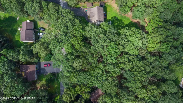 an aerial view of residential house with outdoor space and trees all around