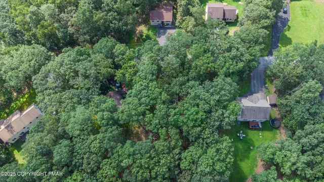 an aerial view of residential house with outdoor space and trees all around