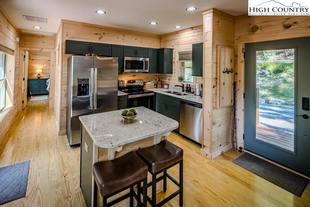 a kitchen with stainless steel appliances granite countertop a refrigerator a stove top oven a sink with island and chairs