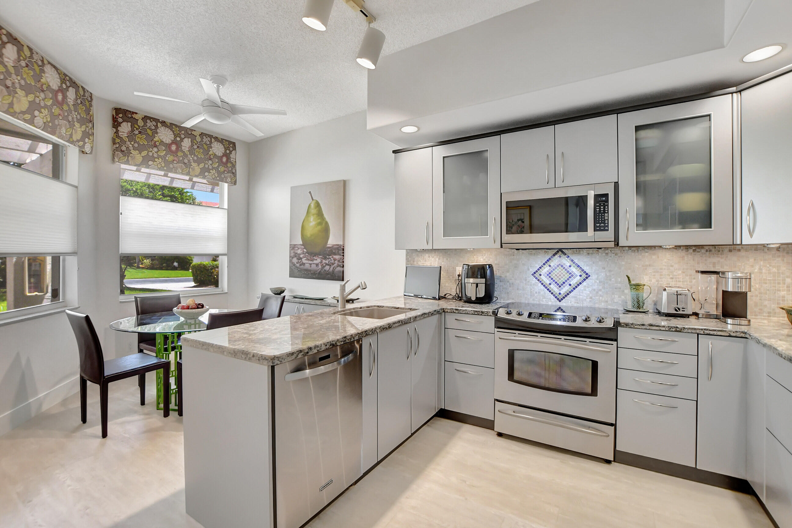 5801 Northwest 24th Avenue, Unit 1004 Boca Raton, FL 33496 - Photo 15 of 65 a kitchen with stainless steel appliances granite countertop a stove top oven a sink dishwasher a dining table and chairs with wooden floor