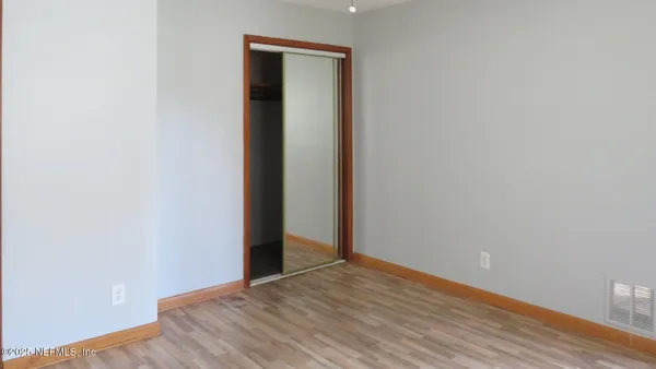a view of an empty room with wooden floor and closet