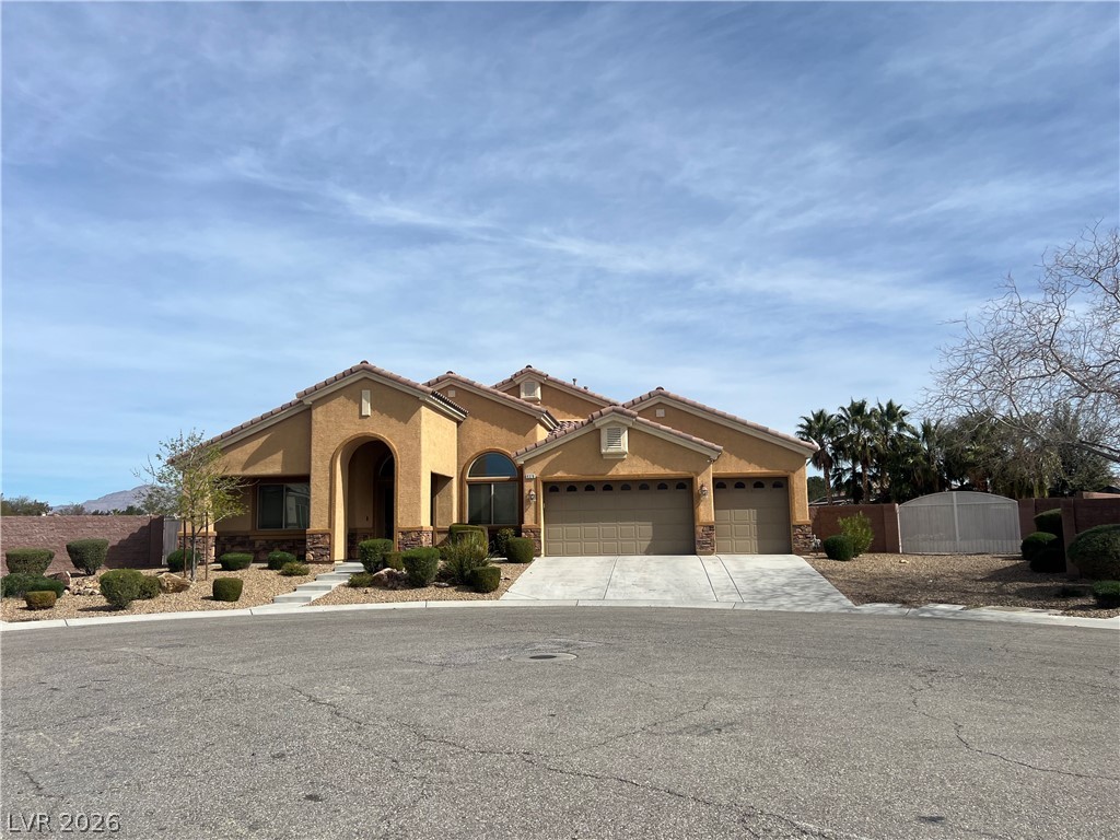 Mediterranean / spanish-style home featuring stucco siding, stone siding, an attached garage, concrete driveway, and a tile roof