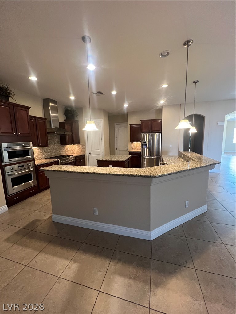 Undisclosed Address Las Vegas, NV 89129 - Photo 17 of 33 Kitchen featuring light stone counters, light tile patterned floors, range hood, fridge, and hanging light fixtures