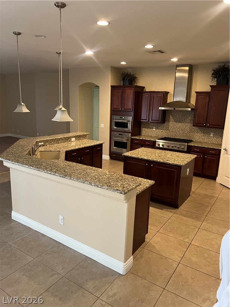 Undisclosed Address Las Vegas, NV 89129 - Photo 18 of 33 Kitchen with pendant lighting, range hood, light stone countertops, light tile patterned floors, and arched walkways