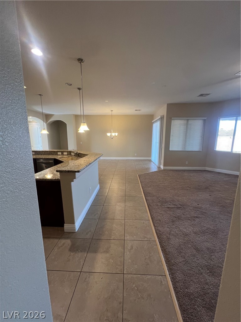 Undisclosed Address Las Vegas, NV 89129 - Photo 32 of 33 Kitchen with light tile patterned flooring, light stone counters, a chandelier, dishwasher, and open floor plan