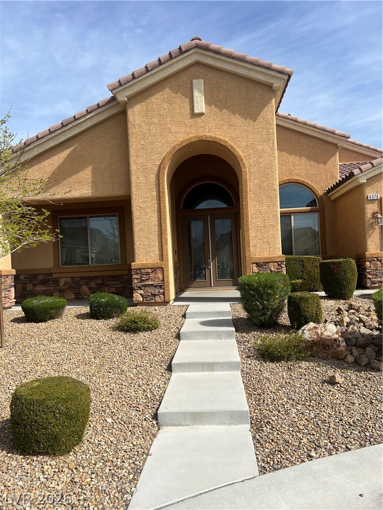 Undisclosed Address Las Vegas, NV 89129 - Photo 2 of 33 Doorway to property with a tiled roof, french doors, and stone siding