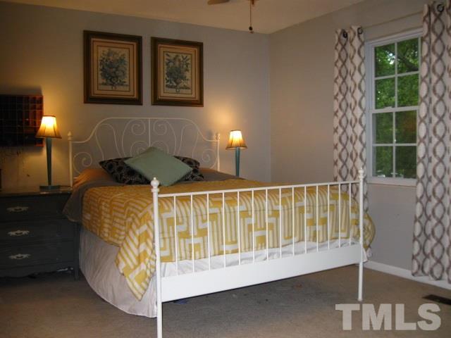 6455 New Market Way Raleigh, NC 27615 - Photo 13 of 18 a bed sitting in a bedroom next to a lamp