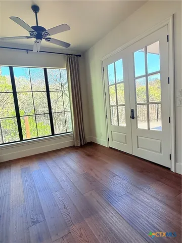 a view of an empty room with wooden floor and a window