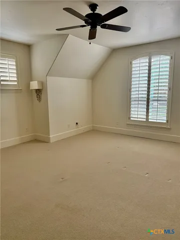 an empty room with a ceiling fan and windows