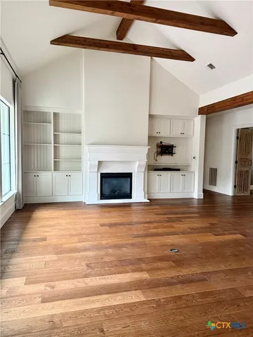 a view of empty room with wooden floor and fireplace