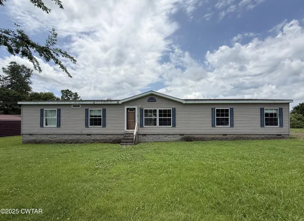 a house that is sitting in the grass with large trees
