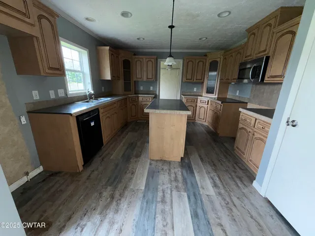 a large kitchen with stainless steel appliances wooden floors wooden cabinets a counter space and a sink