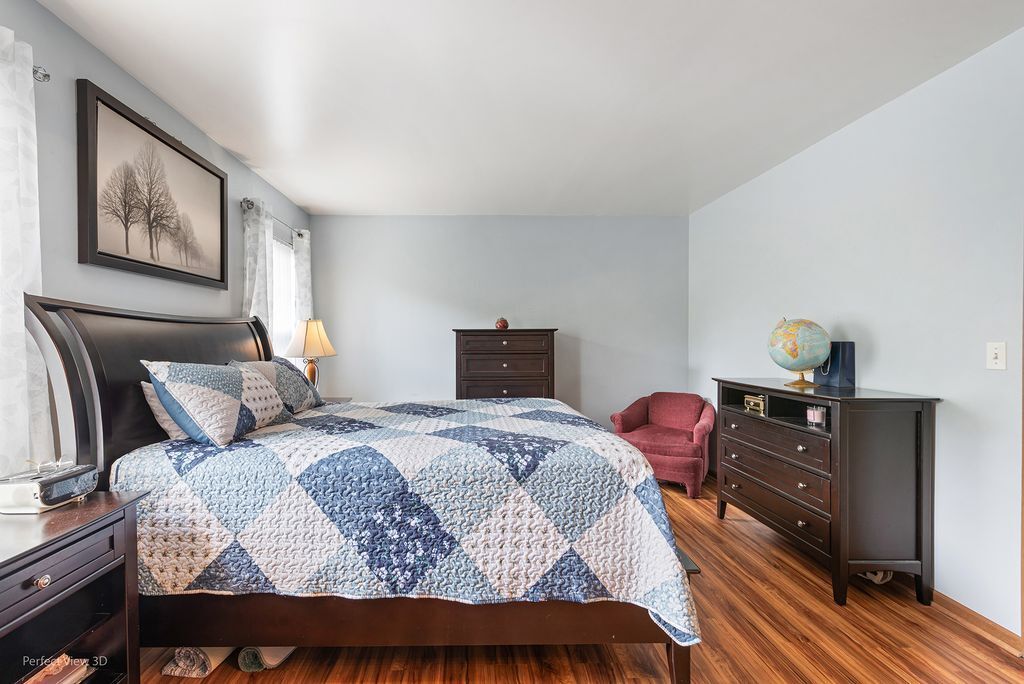 22202 West Niagara Trail, Unit 22202 Plainfield, IL 60544 - Photo 17 of 24 a bedroom with a bed and wooden floor