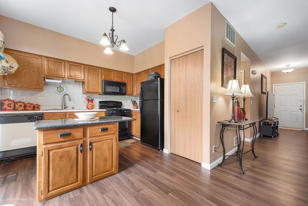 22202 West Niagara Trail, Unit 22202 Plainfield, IL 60544 - Photo 8 of 24 a kitchen with kitchen island granite countertop wooden floors and stainless steel appliances