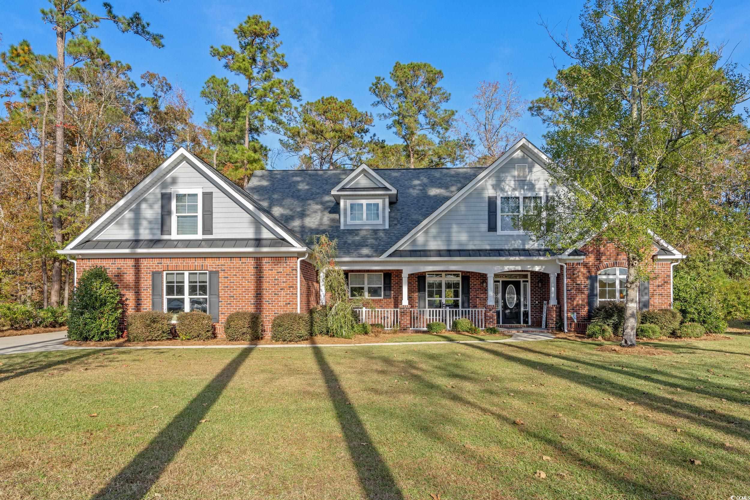 View of front of house with a porch, brick siding, and a front yard