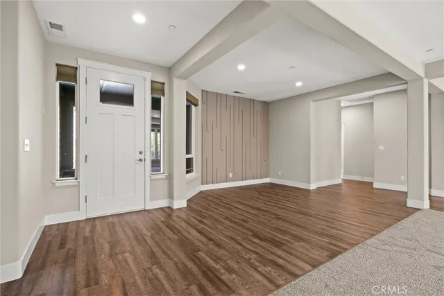 a view of an empty room with a window and wooden floor