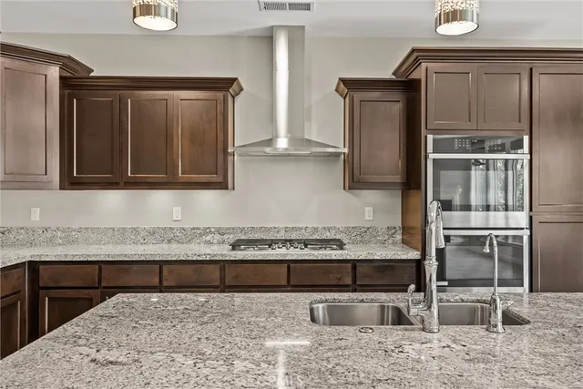 a kitchen with stainless steel appliances granite countertop a refrigerator a sink and a stove