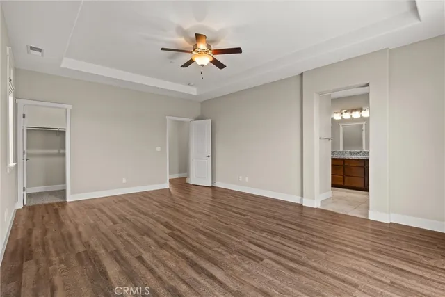 an empty room with windows and chandelier fan