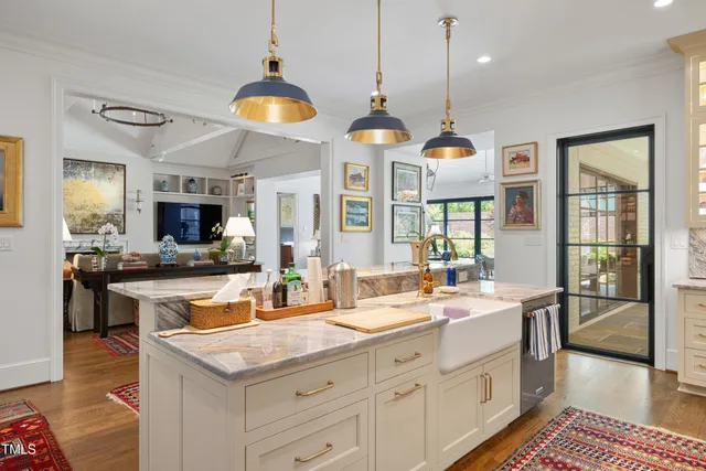 a kitchen with a stove a sink a center island and living room view