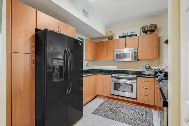 a kitchen with stainless steel appliances granite countertop a refrigerator a stove and a sink