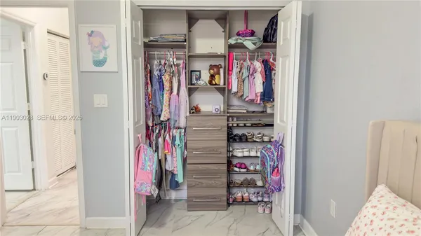 a view of walk in closet with clothes and shoes