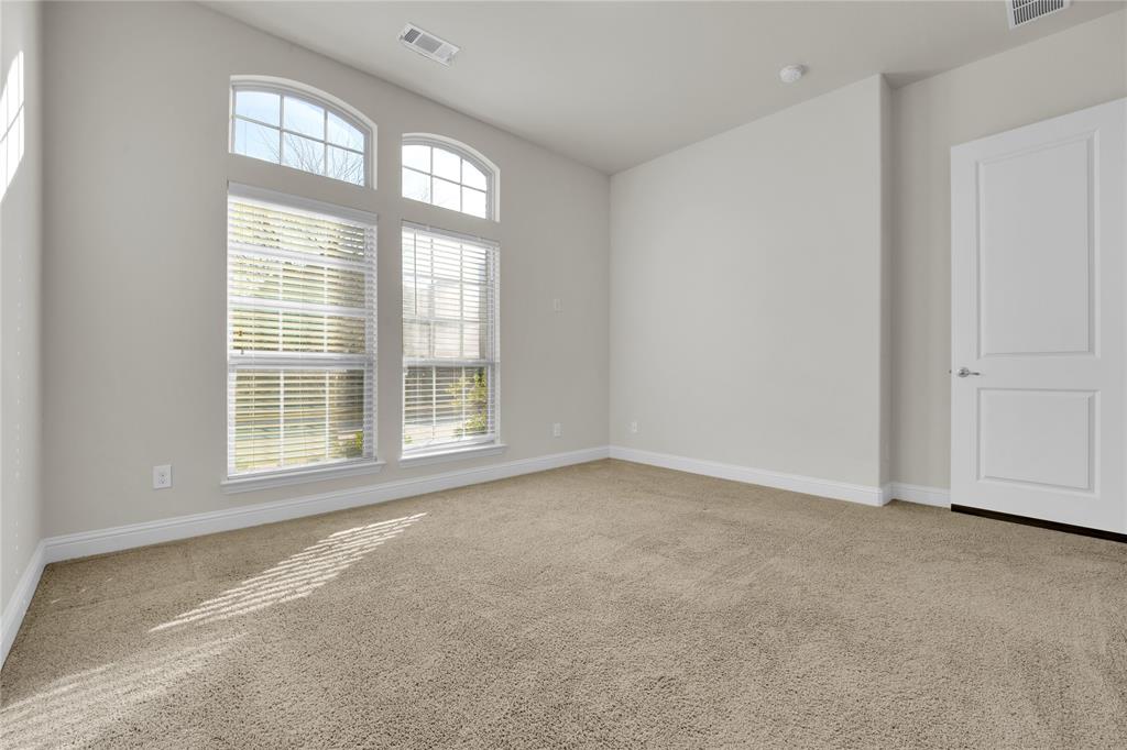 1011 Prairie Ridge Lane Arlington, TX 76005 - Photo 16 of 32 Carpeted interior space featuring a large window array with horizontal blinds, arched transom windows, vaulted ceiling, and a paneled interior door