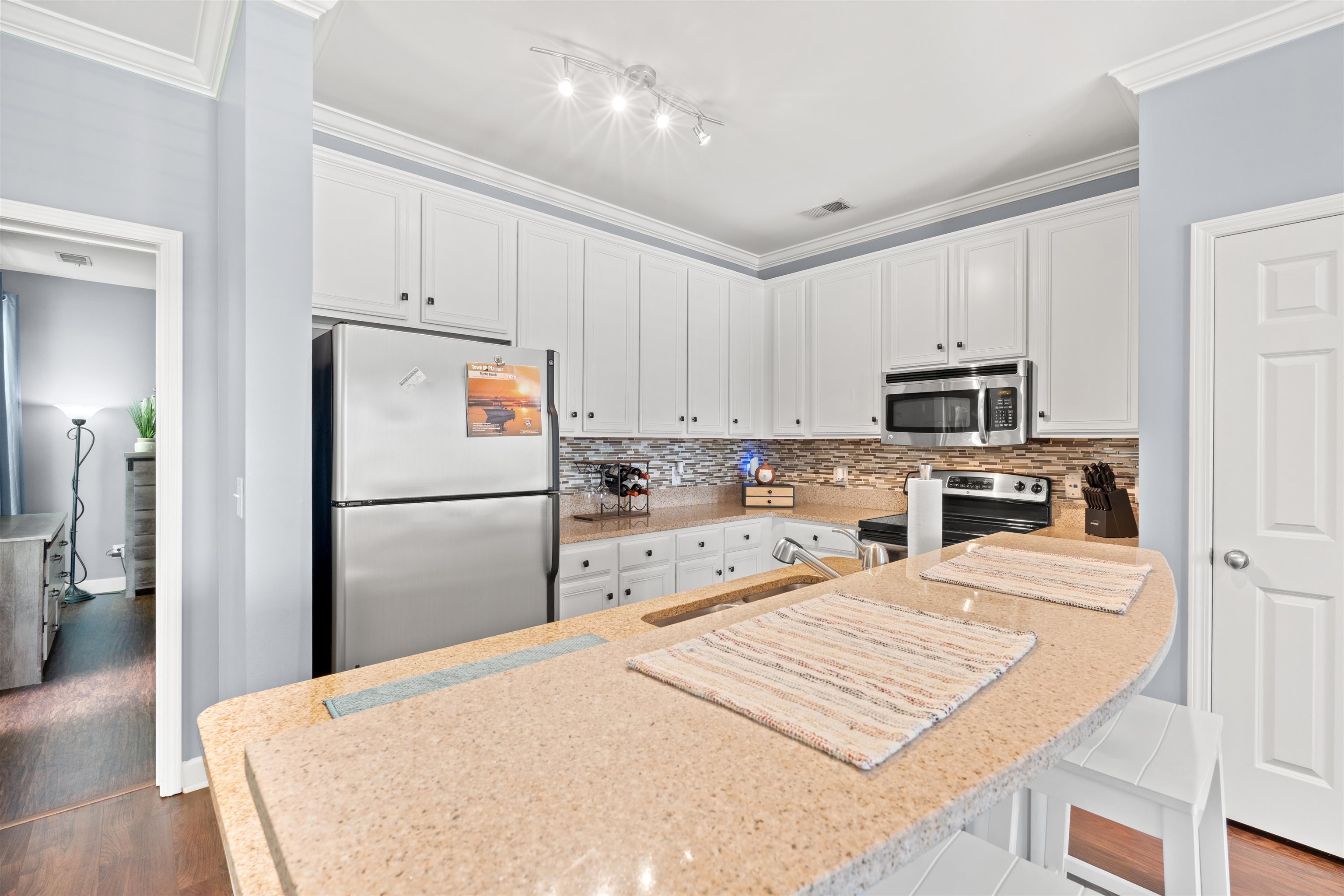 3512 Alexandria Avenue, Unit 18 Myrtle Beach, SC 29577 - Photo 8 of 31 Kitchen with crown molding, stainless steel appliances, white cabinets, a kitchen breakfast bar, and light stone counters