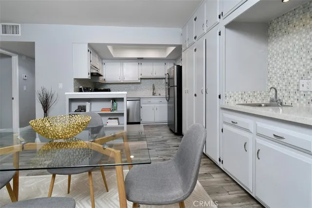 a kitchen with stainless steel appliances granite countertop a sink a stove a refrigerator a dining table and chairs