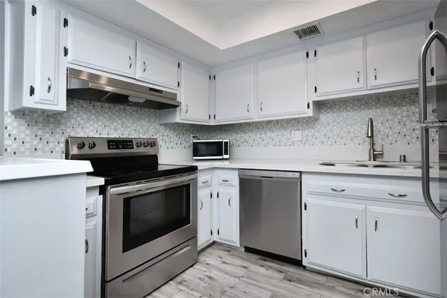a kitchen with stainless steel appliances granite countertop white cabinets a sink and dishwasher