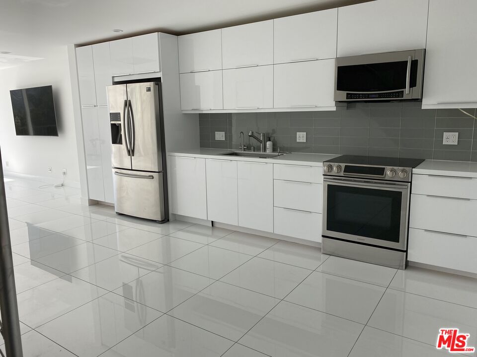 23901 Civic Center Way, Unit 114 Malibu, CA 90265 - Photo 22 of 38 a kitchen with stainless steel appliances granite countertop a stove a microwave and a refrigerator