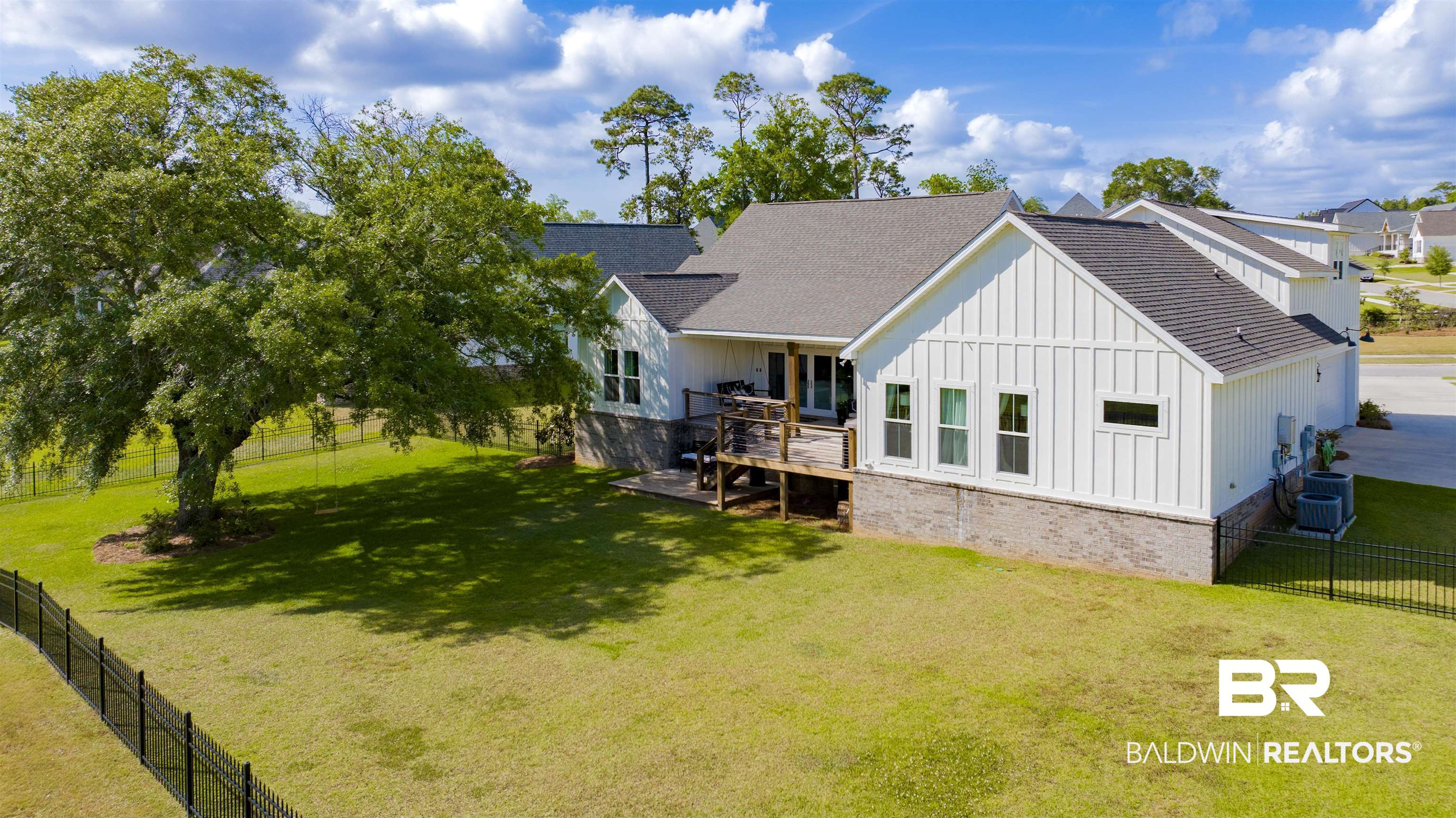 21621 Veranda Boulevard Fairhope, AL 36532 - Photo 50 of 51 Back of property with board and batten siding, a deck, a fenced backyard, a yard, and a shingled roof