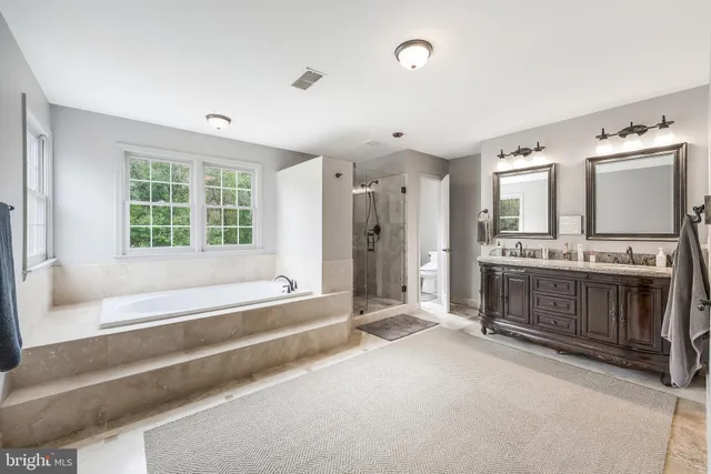 a spacious bathroom with a tub sink and mirror