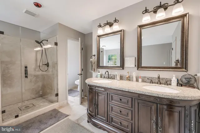 a bathroom with a double vanity sink mirror and shower