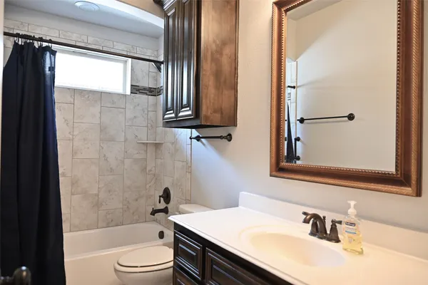 a bathroom with a granite countertop sink toilet a mirror and shower