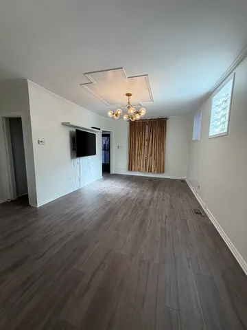 an empty room with wooden floor and chandelier