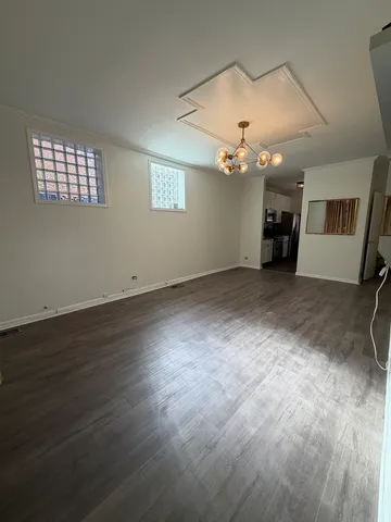 an empty room with wooden floor chandelier fan and windows