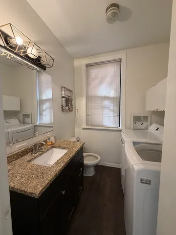 a bathroom with a granite countertop sink a toilet a mirror and shower