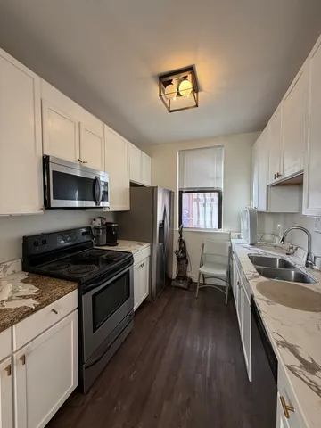 a kitchen with granite countertop a stove top oven a sink dishwasher a dining table and chairs with wooden floor