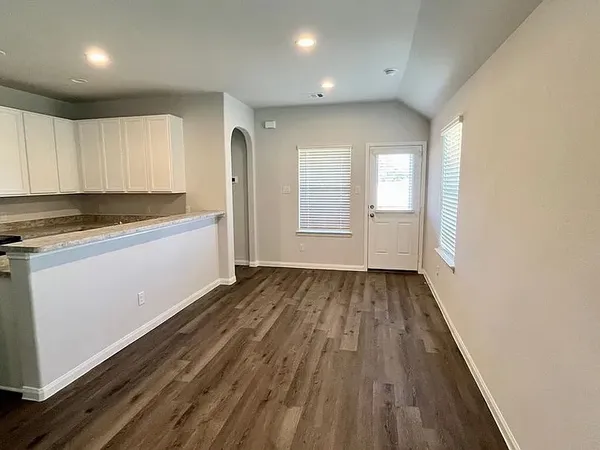 an empty room with wooden floor and windows