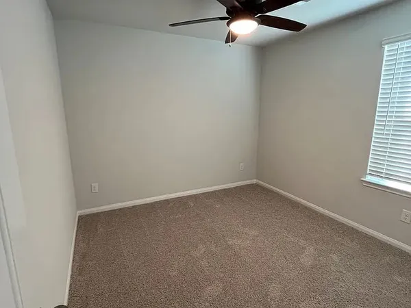 an empty room with a window and a fan