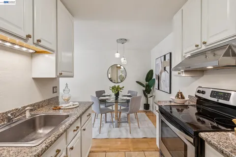 a kitchen with stainless steel appliances granite countertop a stove a refrigerator a dining table and chairs with wooden floor