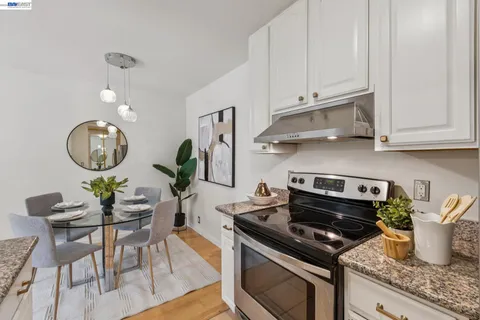 a kitchen with stainless steel appliances granite countertop a sink dishwasher stove and white cabinets with wooden floor