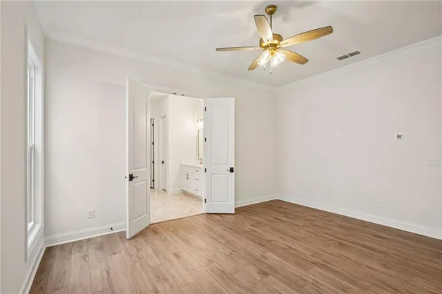 an empty room with wooden floor and fan