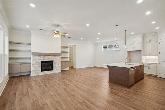 a living room with stainless steel appliances kitchen island wooden floors and fireplace