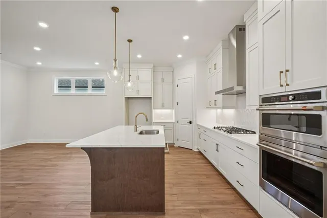 a large kitchen with stainless steel appliances kitchen island granite countertop a stove a sink and white cabinets