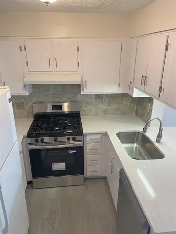 a kitchen with granite countertop white cabinets and stainless steel appliances