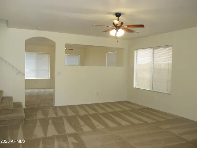 an empty room with a chandelier fan and windows