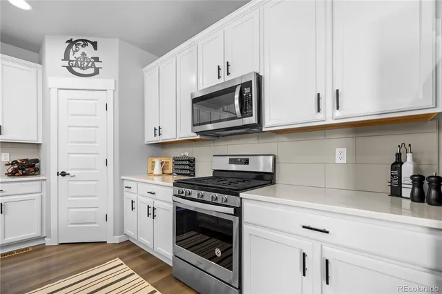 a kitchen with granite countertop white cabinets and stainless steel appliances