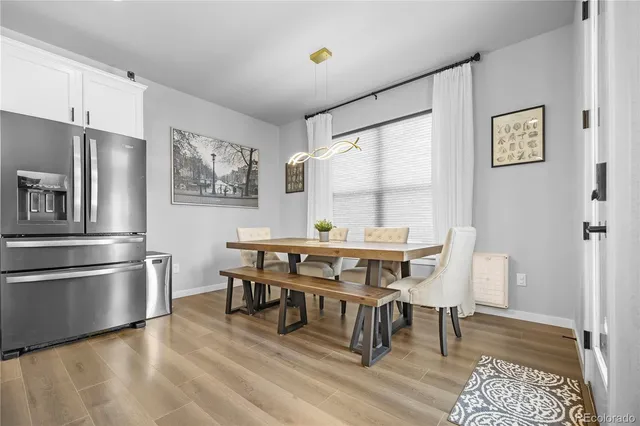 a dining room with stainless steel appliances granite countertop a dining table and chairs with wooden floor