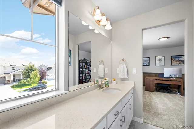 a spacious en suite bathroom with a granite countertop sink a large mirror and a bathtub